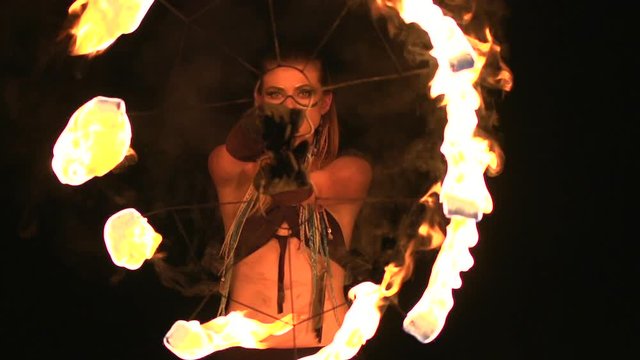 Young girl dances with burning torches made in shape of fans at fire show