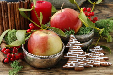 Christmas decor with candle, apples, gingerbread cookies and mistletoe.