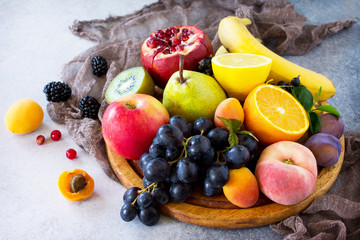 Fresh mixed fruits on a gray stone or slate background. The concept of a healthy diet.