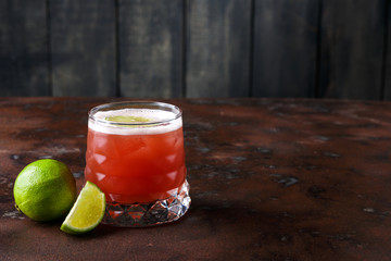 Red cocktail with lime on brown table background