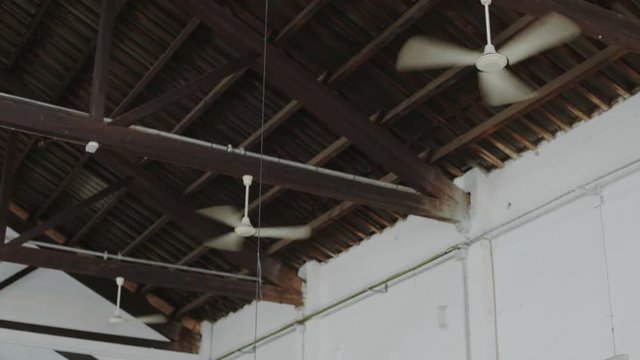Three symmetrical and identical ceiling fans or ventilators attached to roof of huge industrial open space move air from top to bottom, used as air conditioner in modern contemporary designed building