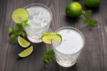 Fototapeta premium Fresh cocktail with lime, ice and mint on a rustic background. Copy space, top view