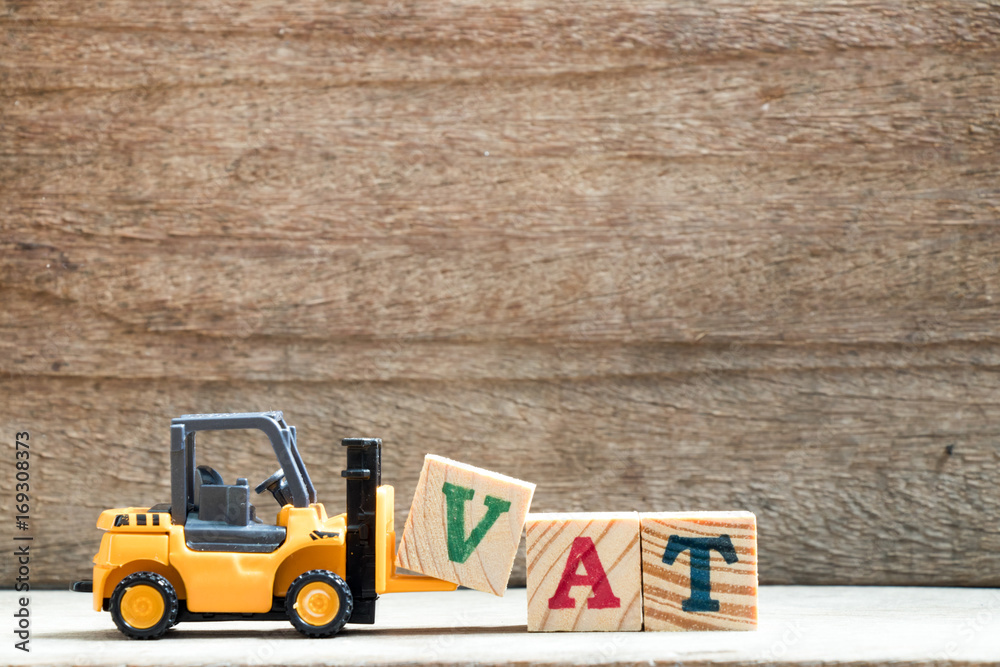 Poster Toy plastic forklift hold block V to compose and fulfill wording VAT on wood background