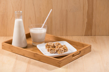 Dairy products. A bottle of milk and glass of milk serve with almond candies on a wooden table.