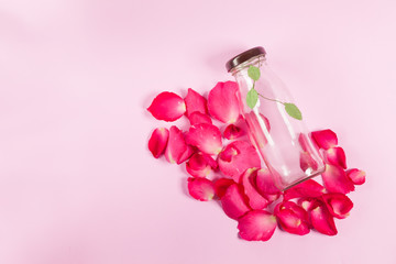bottle and rose petals On the pink background 
