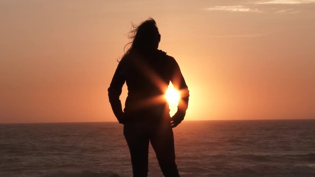 Model released woman silhouette stands on viewpoint watching the sunset from the Oregon coast.