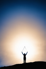Silhouette image of man with hands raised at a height