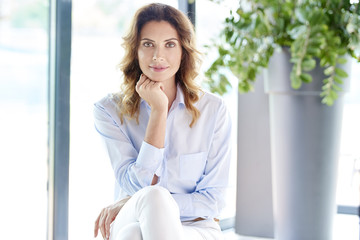 Smiling middle aged beauty. Portrait of a beautiful middle aged woman looking at camera and smiling while sitting at home. 