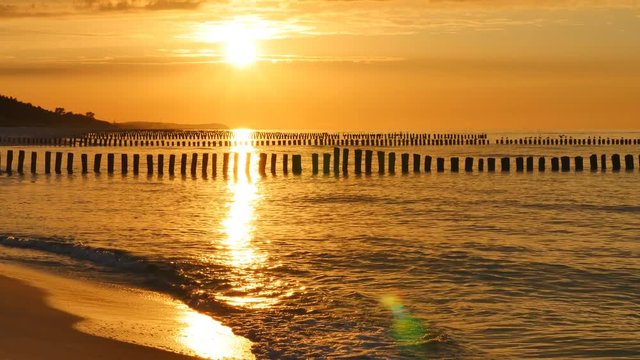 Wooden breakwaters and sunset over the Baltic Sea