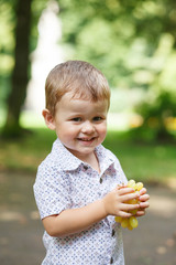 Cute boy eating grapes outdoors.