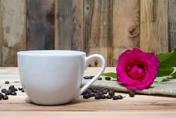 Pink rose coffe cup and coffee beans on wooden table