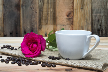 Pink rose coffe cup and coffee beans on wooden table
