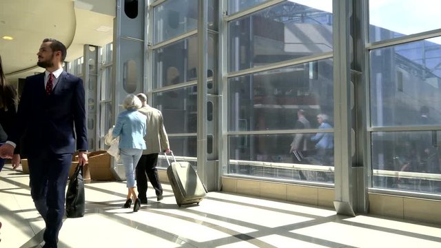 Two senior people walking together with a suitcase in airport terminal