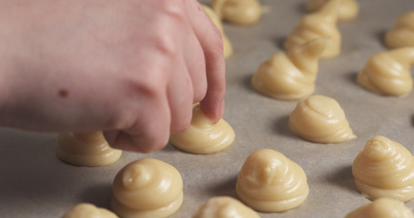 female hand tapping tops of profiteroles with wet finger