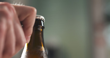 man hand opening brown beer bottle closeup