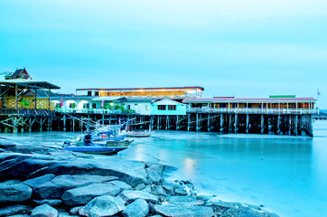 The sand beach and sea with fishing boat that parked on the beachfront with rock and reef in morning with sunrise, Beautiful sky with sea and fishing boat and rock with house in the seafront.