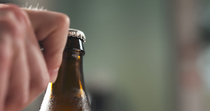 Man Hand Opening Brown Beer Bottle Closeup