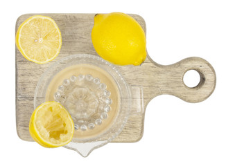 Two  lemons and juice squeezed from one half of lemon on cutting board. Isolated on white background