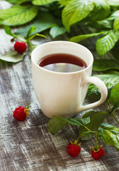 Tea with raspberries and raspberries on a wooden background. Place under the text