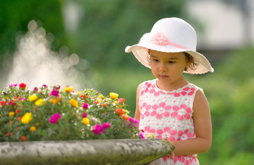 Little girl in the garden admiring flowers