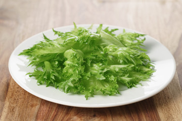green frillice lettuce on white plate on wooden table