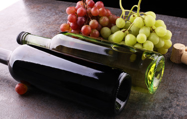 Obraz premium Bottle of white and red wine, grape and corks on wooden table