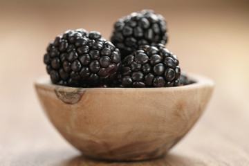 blackberries in small wood bowl on wooden table