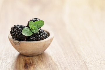 Fototapeta na wymiar blackberries in small wood bowl on wooden table