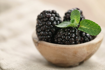 Fototapeta na wymiar blackberries in small wood bowl on wooden table