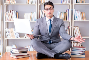 Businessman student in lotus position meditating with a laptop i