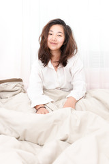 Beautiful woman waking up in her bed in the bedroom, she is smiling after wake up.