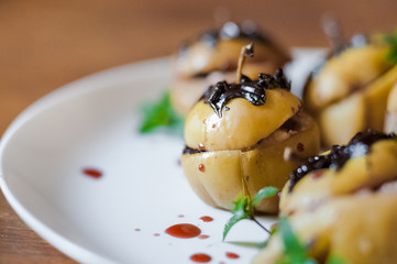 Baked apples with cottage cheese, chocolate, nuts, mint. Apples on a white plate