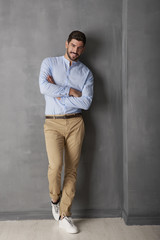 Confident young man portrait. Close-up portrait of a young man standing at grey wall in the studio.
