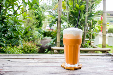 Thai tea ( Cha-Thai ) on wood table with nature background with copy space.