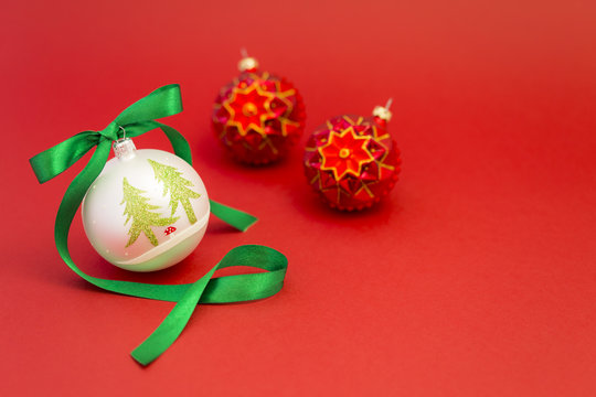 Beautiful white and red christmas balls with green silky ribbon on red background.