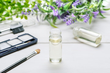 Cosmetic items on a white wooden table with lavender flower and glass vial with liquid inside