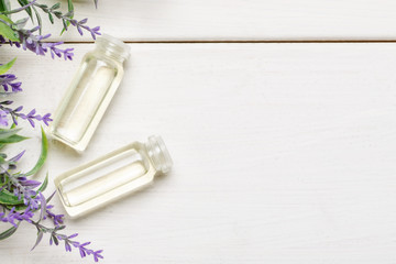 Two bottles with liquid inside and lavender flower near on a white wooden table, flat lay template with text space