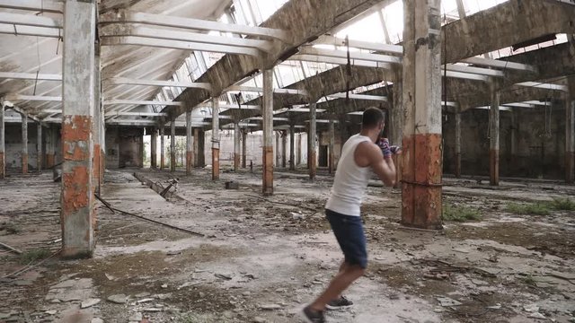 Back view of male boxer doing shadow boxing exercise in an old abandoned building.