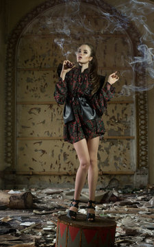 A beautiful girl, a model in a refined outfit in a creative location smokes a pipe. Fashion, style, beauty, portrait.