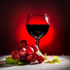 serving glass of red wine and grapevine with green leaf