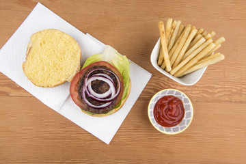 Beef burger with salad, fries and ketchup in a take away container