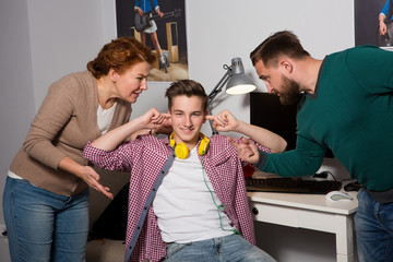 Concept of misundrestanding between generations. Teenage boy closed his ears with hands while...