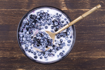 Fresh, ripe forest blueberries with sour cream and honey in black plate.