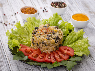 Rice with mushrooms and green lettuce leaves on rustic table background