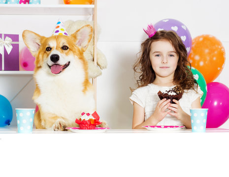 A child and a dog at a festive table eat a cake