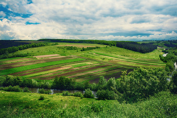 Rural landscape with fields, waves and blue sky with clouds, spring seasonal natural background