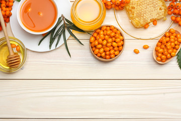 Sea buckthorn in wooden bowl, honey, Sea buckthorn juice on wooden table. top view with copy space
