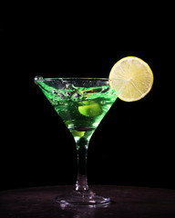 Green cocktail with splash on black background