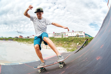 Teen skater rides over a ramp on a skateboard in a skate park
