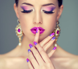 Beautiful girl model with fashion violet make-up and purple design manicure on nails . Jewelry and...